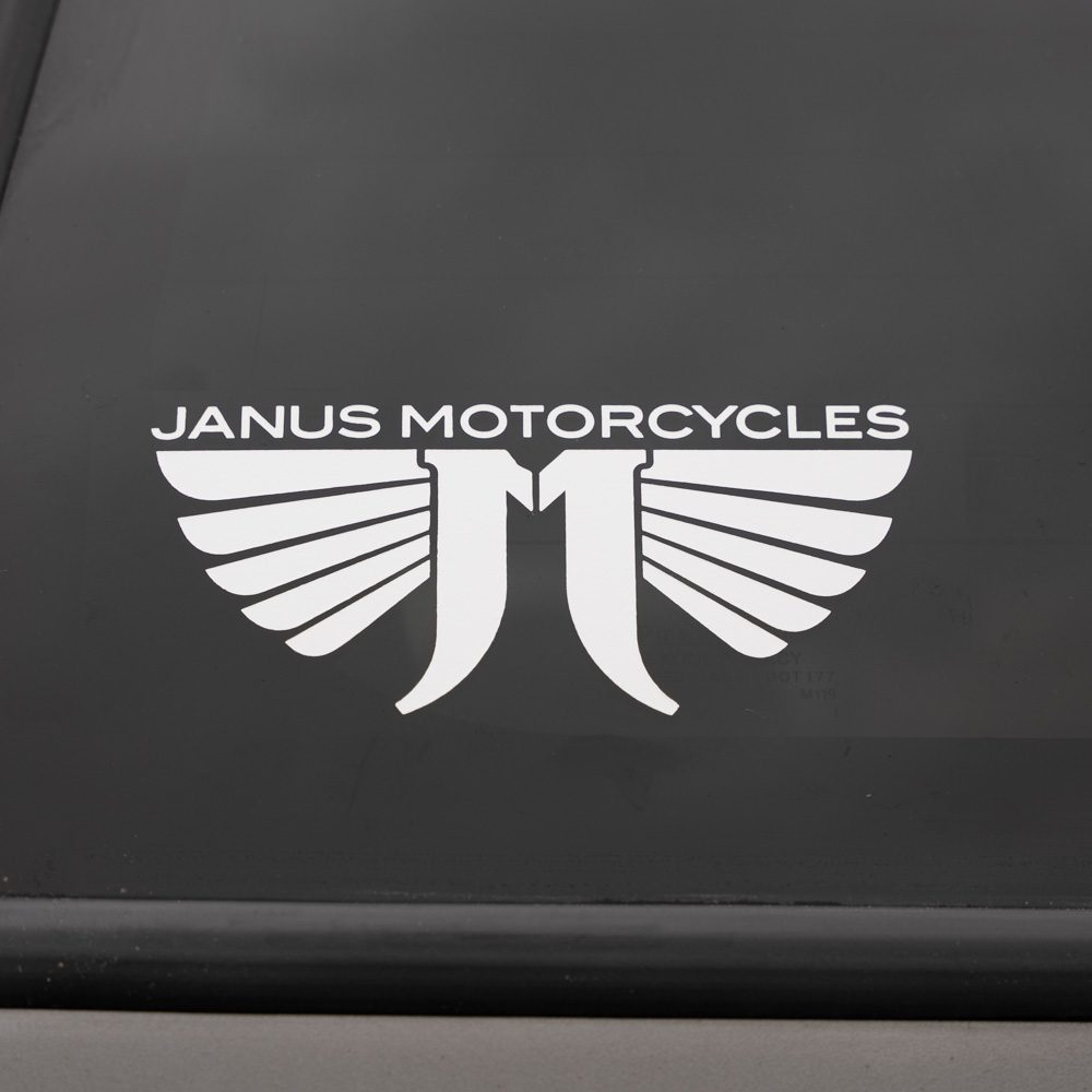 Janus Motorcycles logo with stylized wings on a dark background.