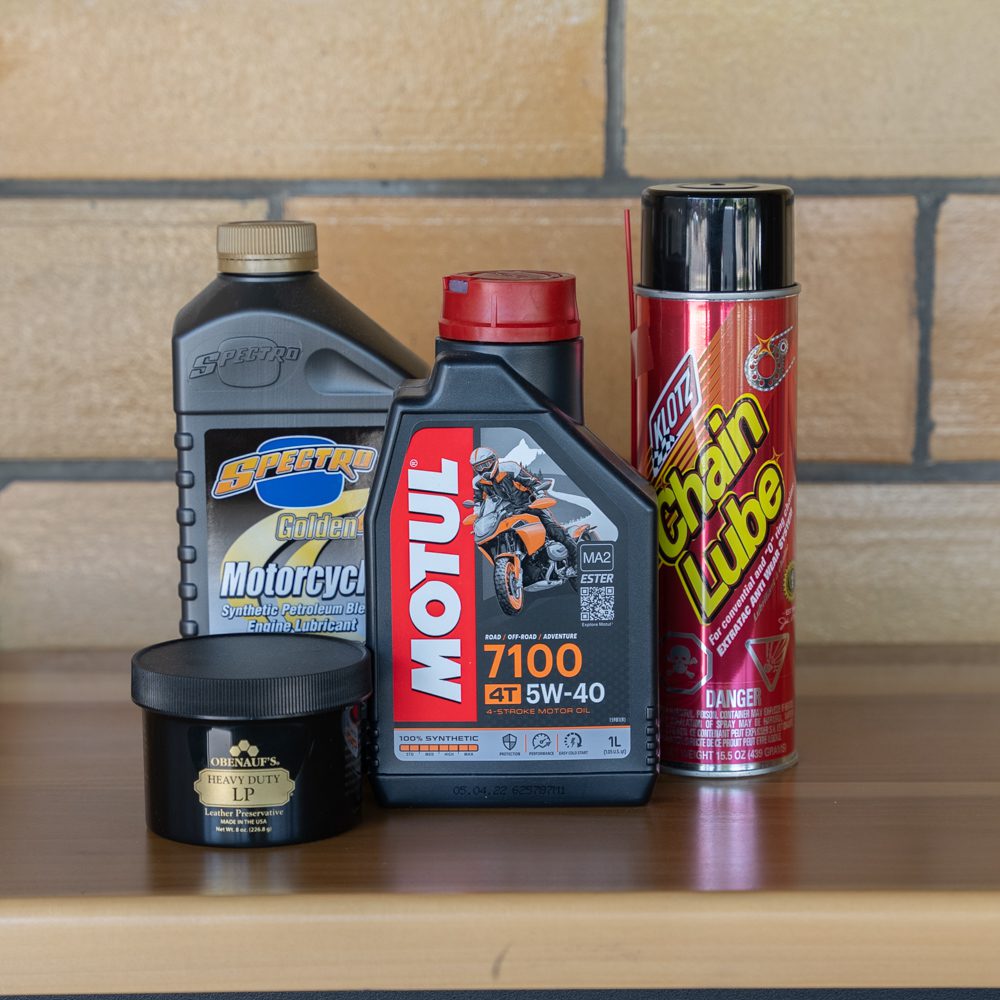 Motorcycle maintenance products including oils and chain lubricant on shelf.