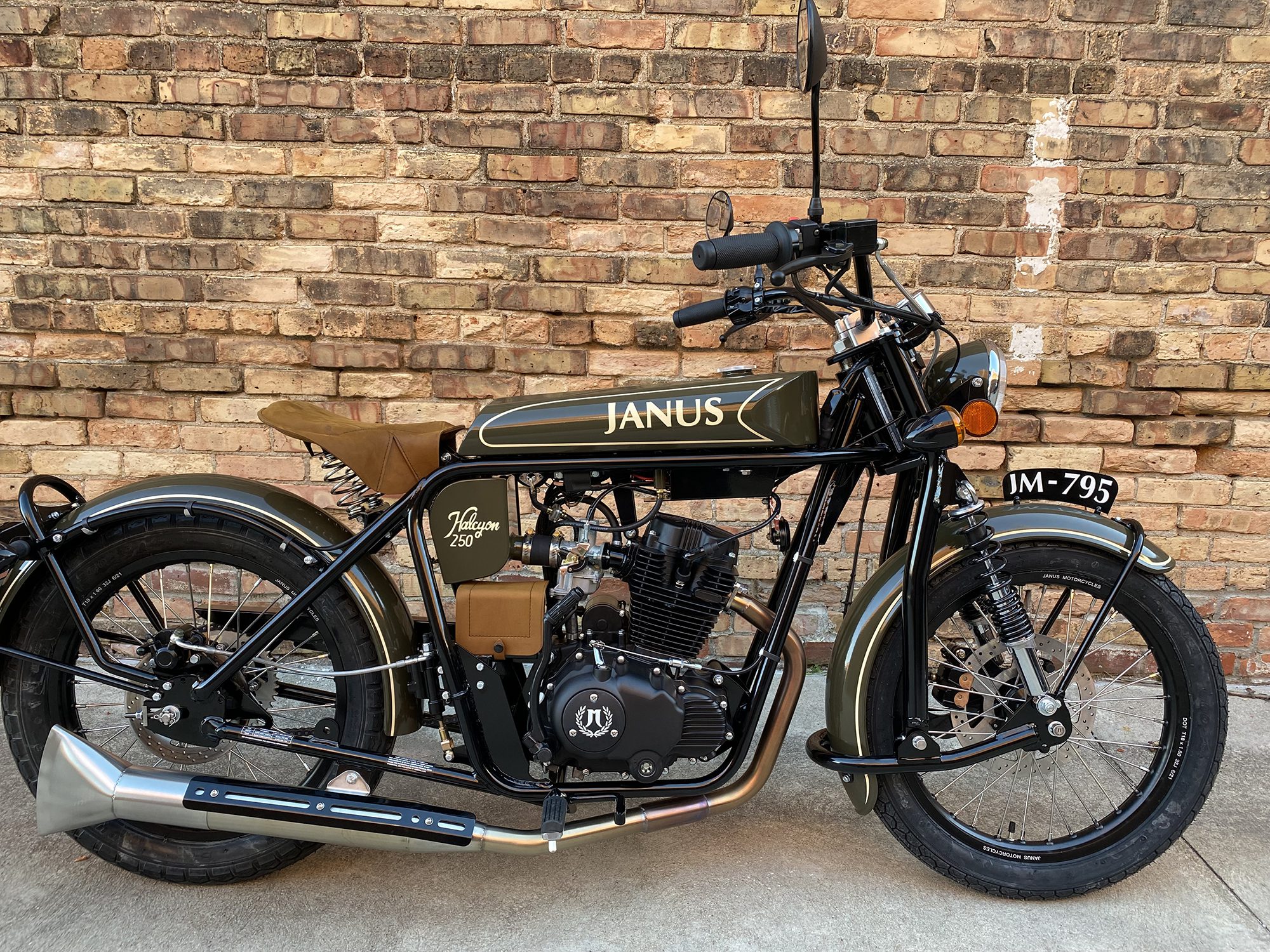 Classic Janus motorcycle parked against a brick wall.