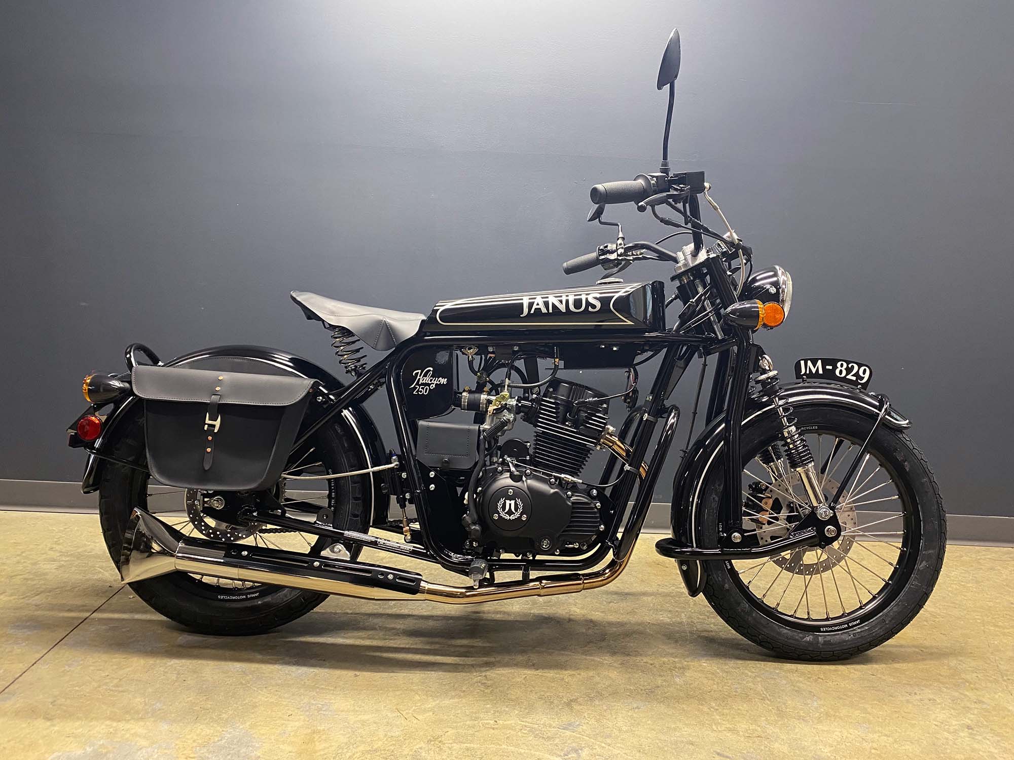 Black Janus Halcyon 250 motorcycle parked indoors with saddlebag.